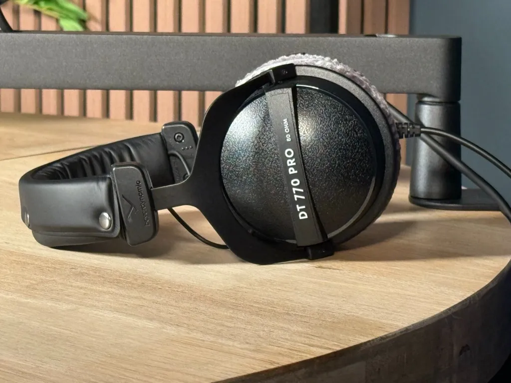 beyerdynamic DT 770 PRO studio headphones on the oak table, with wooden acoustic panels behind
